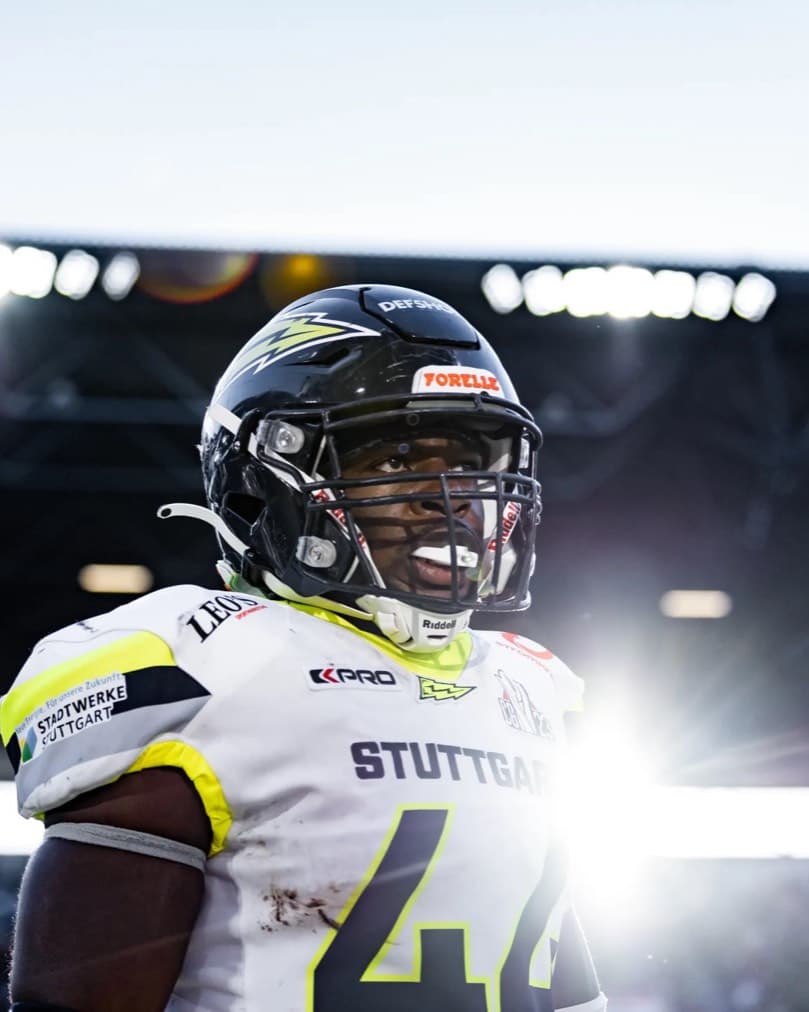 Ein Footballspieler im Gegenlicht der Flutlichtmasten.